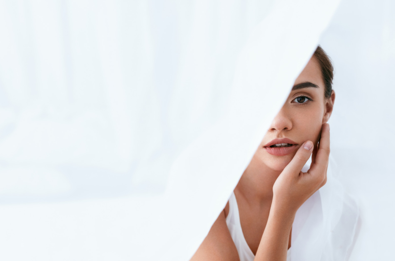 A close-up of a woman with clear, healthy skin touching her face softly, showing the positive effects of her skin care routine.