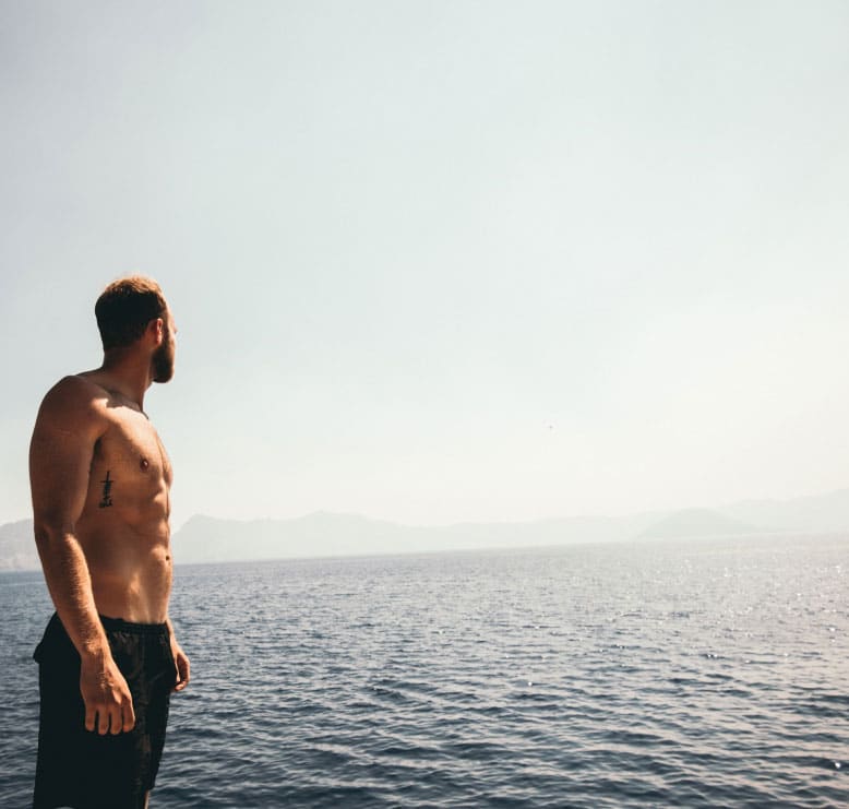 muscular man staring out at the ocean