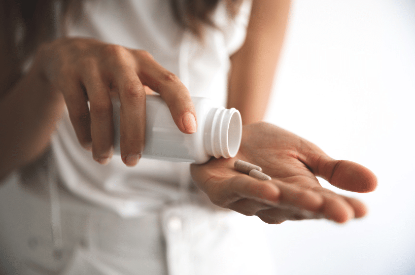 woman pouring out supplements in her hand