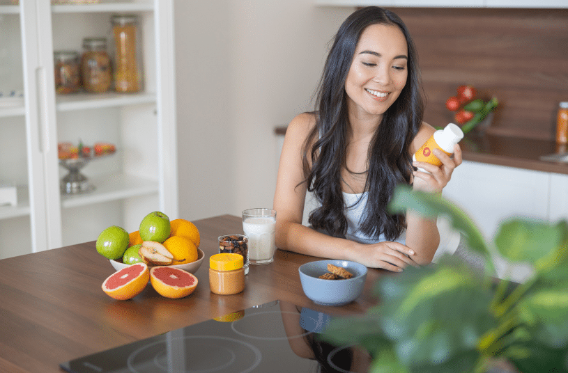 woman sitting at table smiling at supplements