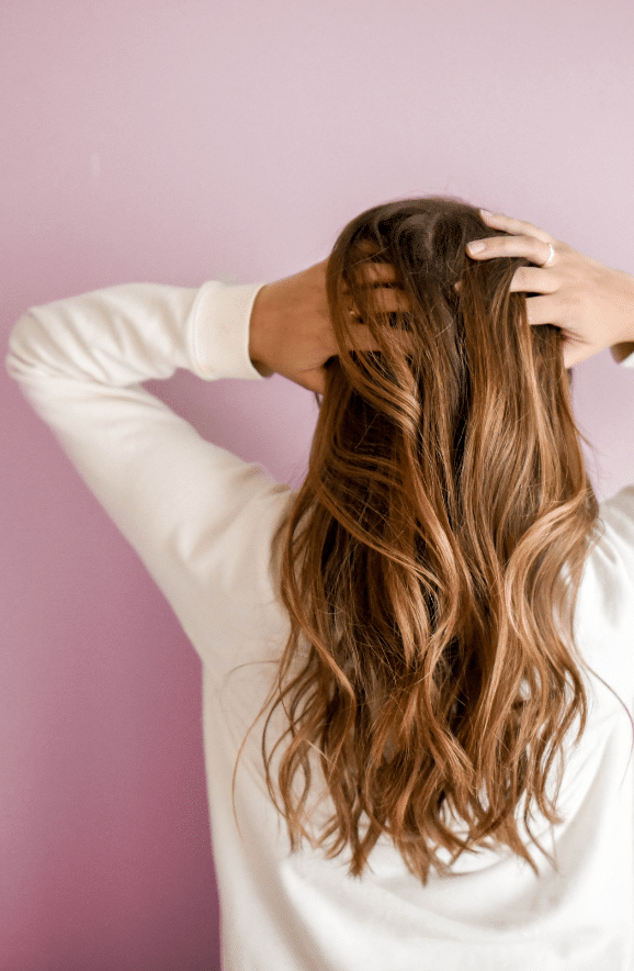 A woman with long, flowing hair overlooks a lake surrounded by palm trees, symbolizing the lush, restored hair achievable through modern hair transplant techniques.