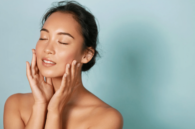 Woman with glowing, youthful skin gently touching her face, showcasing the potential results of Morpheus8 skin treatment.